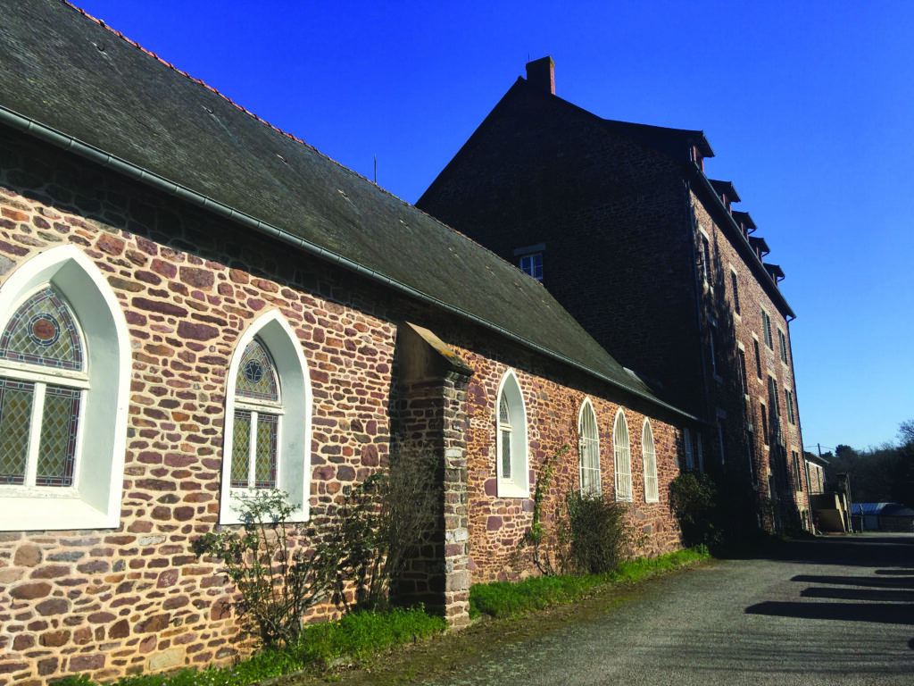 ancien bâtiment de pierres de schiste où était installée la congrégation. On aperçoit au premier plan les vitraux de l'ancienne chapelle, en pierres de schiste également